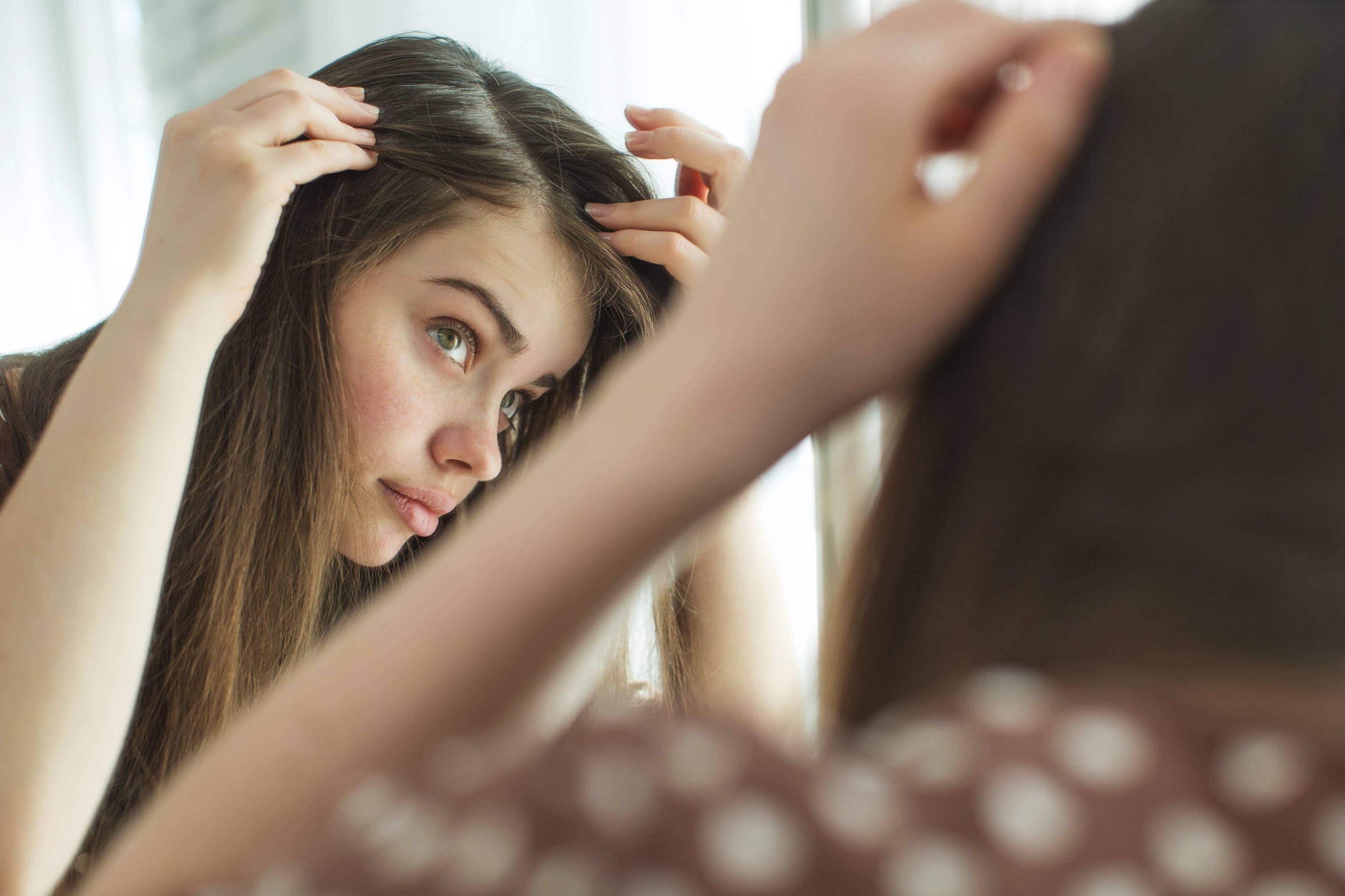 woman looking in the mirror and checking her hair 