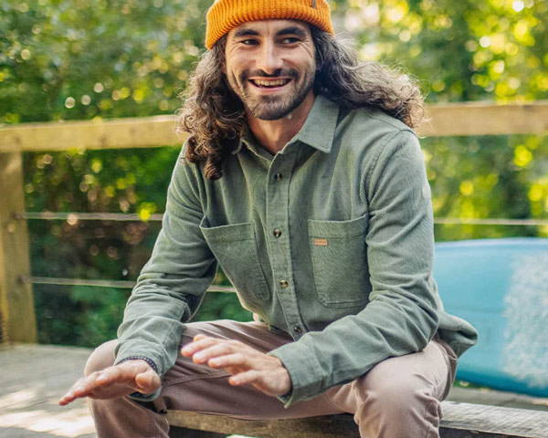 Man in an orange hat wearing recycled cotton corduroy shirt in green from sustainable clothing brand Passenger, based in the UK