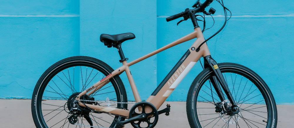 A tan Aventon Pace 500.2 electric city bike against a blue background