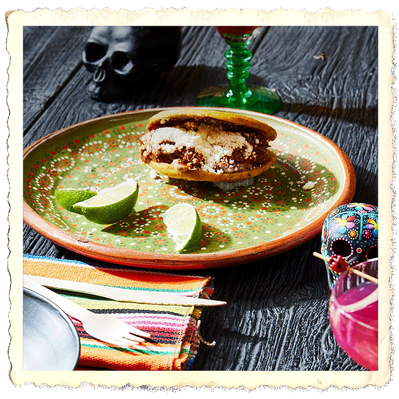 Prepared shallow plate with gordita and lemon slices, and decorating mexican calaveras around.