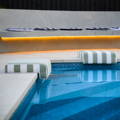 Curved outdoor bench with warm LED strip lighting beside a backyard swimming pool.