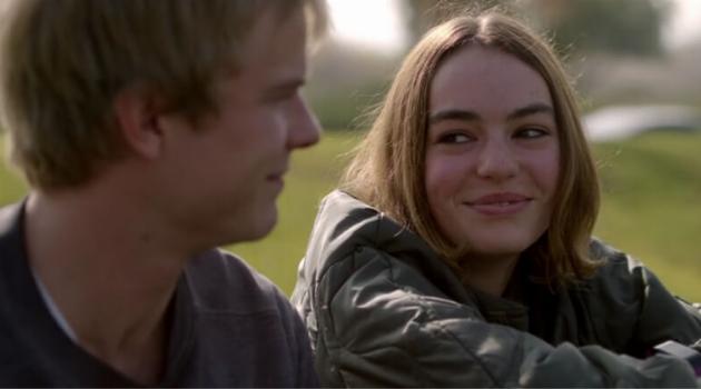 Image of Casey and her friend Evan sitting together on the grass. Casey is smiling at Evan.