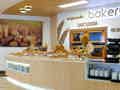 Eine Bäckereitheke mit verschiedenen Broten und Gebäck vor einer Kulisse aus Öfen und dekorativen Weizenähren.