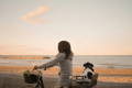Femme a velo en bord de mer avec un chien dans son porte-bagages