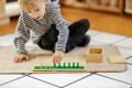 Little boy playing with wooden Montessori pegs in the playroom.