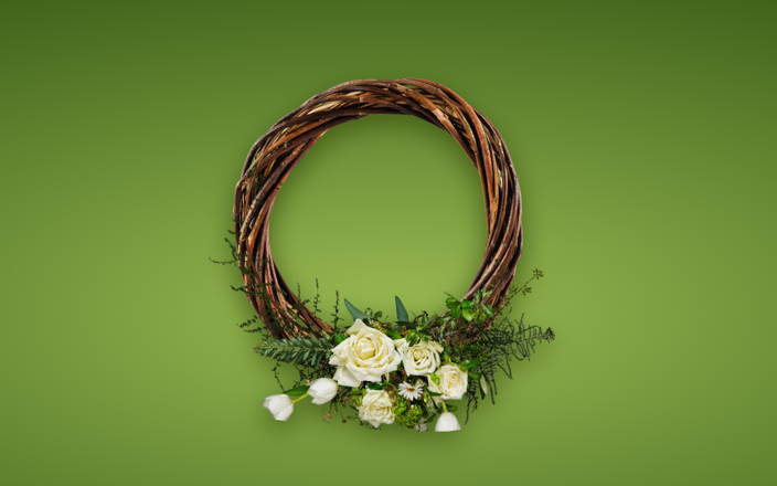 A brown wreath with white spring florals and greenery at the bottom for Confetti's Virtual Floral Wreath Making Class