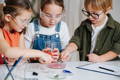Children taking part in science DIY activities at home using coloured water and simple experiment materials.