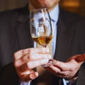 Homme en costume tenant un verre de dégustation Copita rempli de Single Malt Scotch Whisky de la distillerie Glenmorangie dans le nord-ouest des Highlands d'Ecosse
