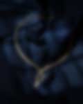 Delicate gold necklace with sparkling diamond pendants displayed on a deep navy satin background.