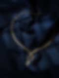 Delicate gold necklace with sparkling diamond pendants displayed on a deep navy satin background.