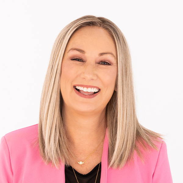 A woman in a pink jacket is leaning on a chair