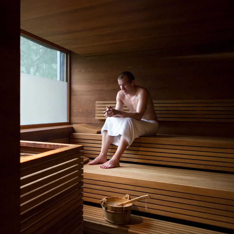 Mann mit Handtuch sitzt in der Sauna