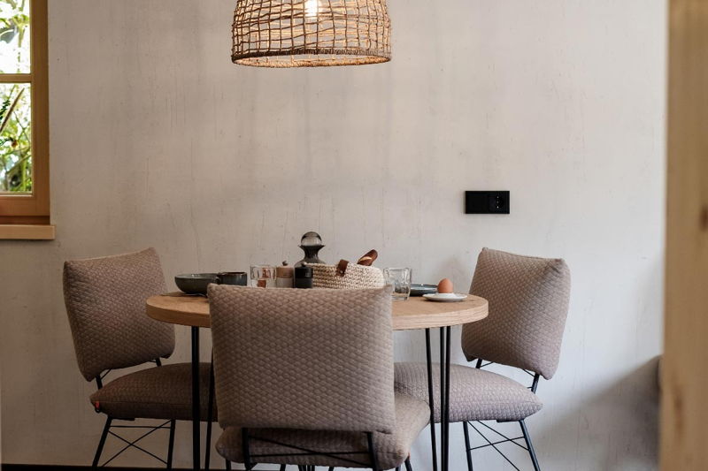 Moderner Essbereich mit rundem Holztisch und geflochtener Pendelleuchte im Apartment Neuer Zeitgeist bei Hugo & Pepi in Mittelberg im Kleinwalsertal