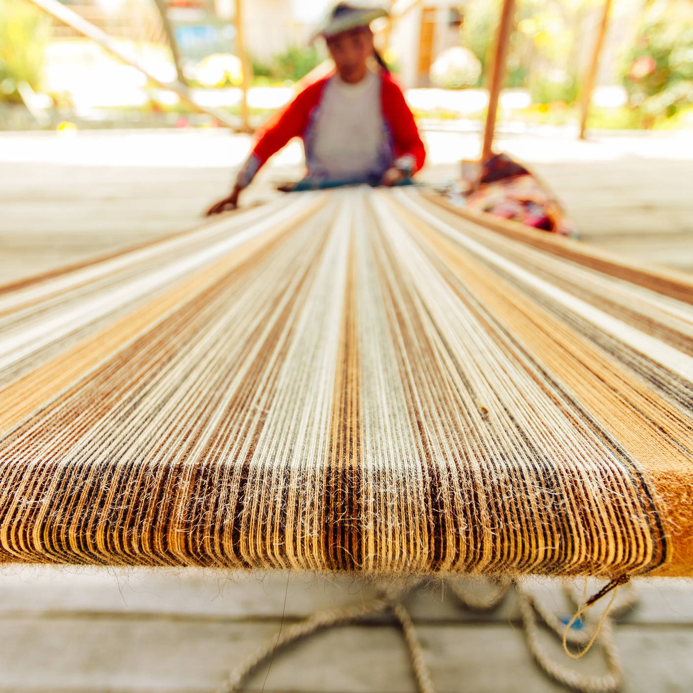 Man using a loom to hand-weave a textile 