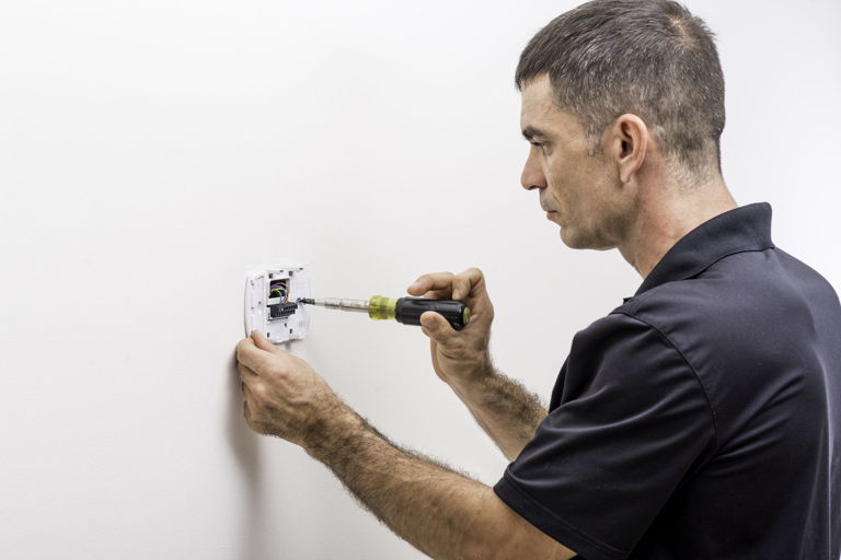 electrician installing a smart thermostat