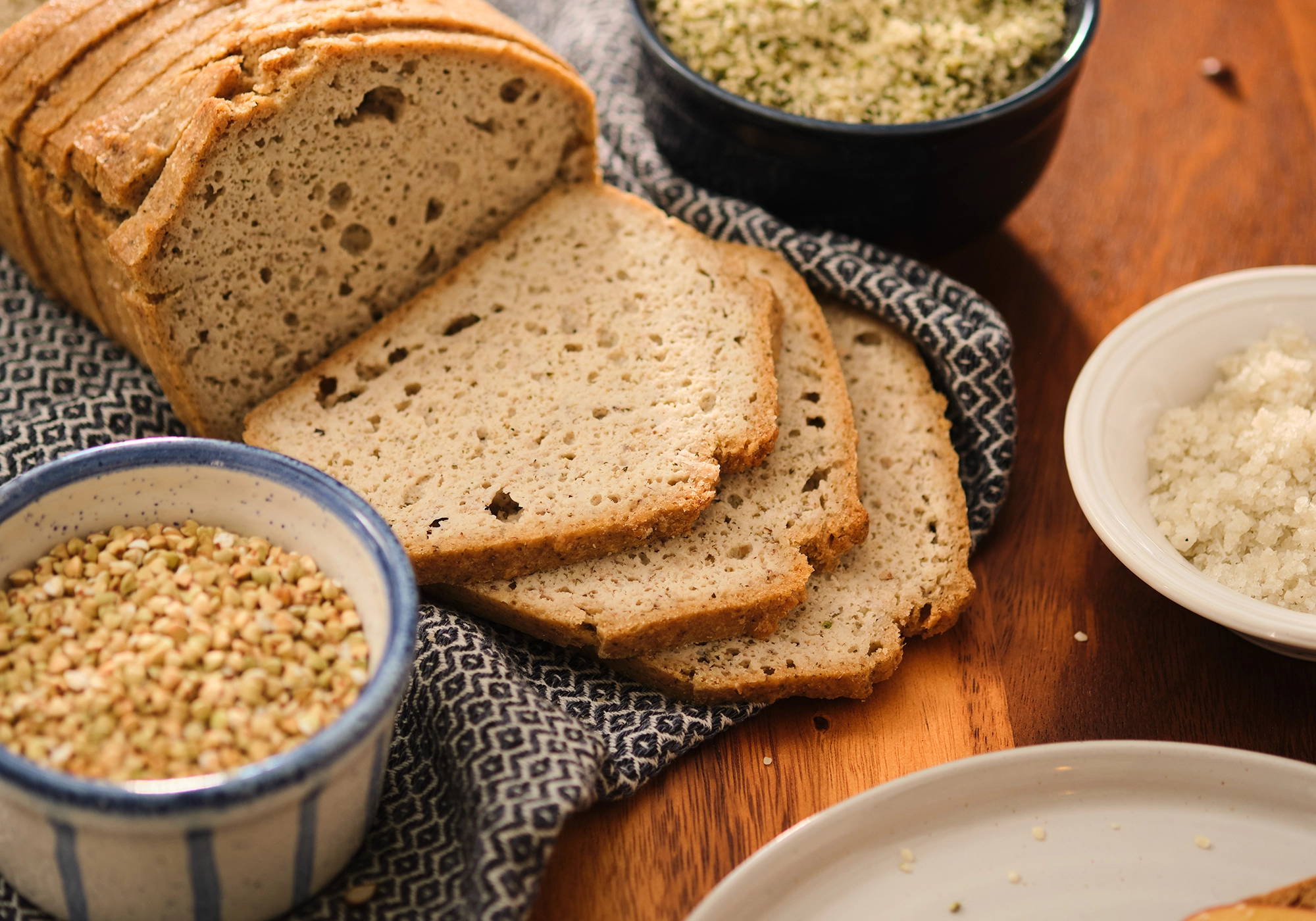 PACHA hemp loaf slices with buckwheat and salt in the background.