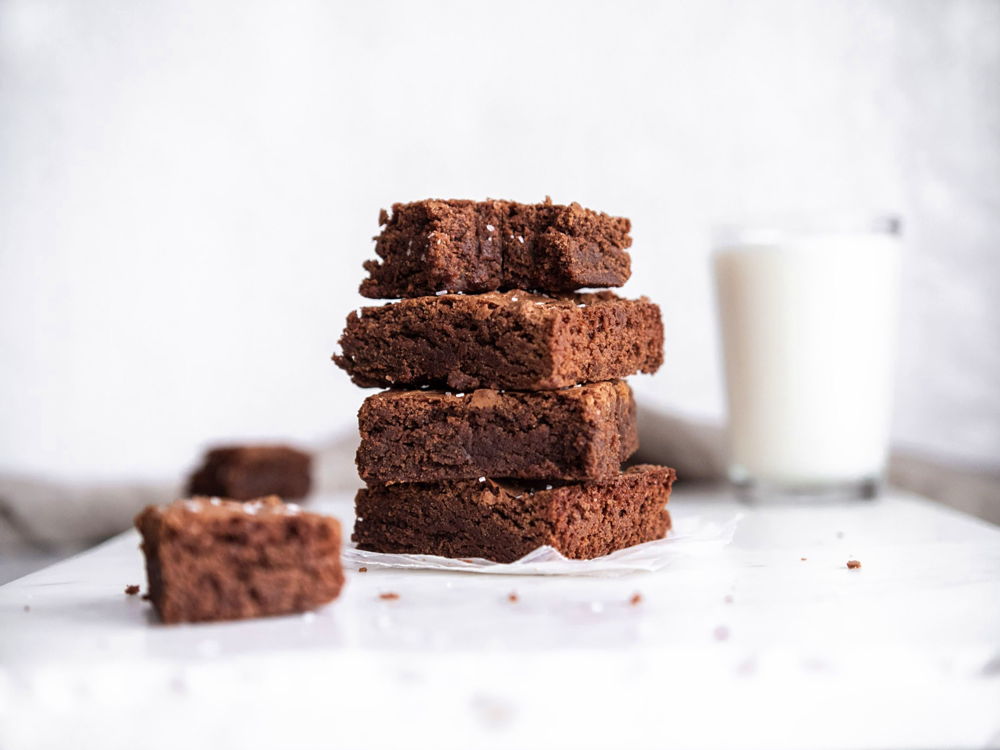 Chocolaty brownies stacked high with a glass of milk