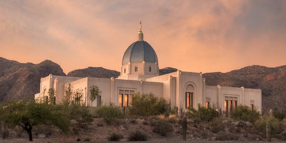 Tucson Temple standing in front of deseter mountains and orange clouds.