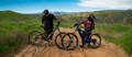 Two mountain bike riders stopped on trail fist bumping