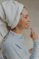 woman with a towel on her head applying skincare for clogged pores
