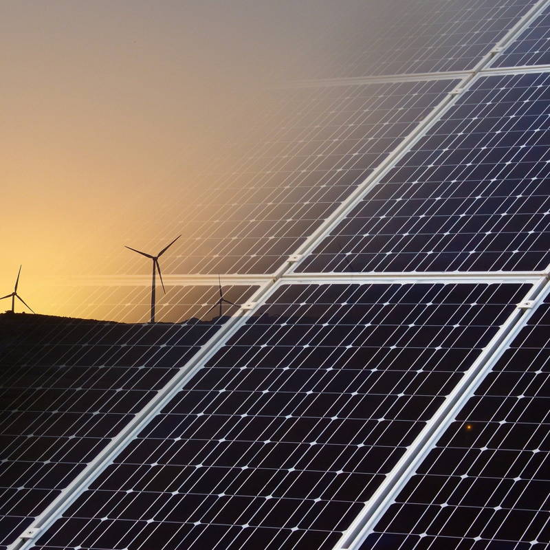 Zonnecellen en windmolens in schemer