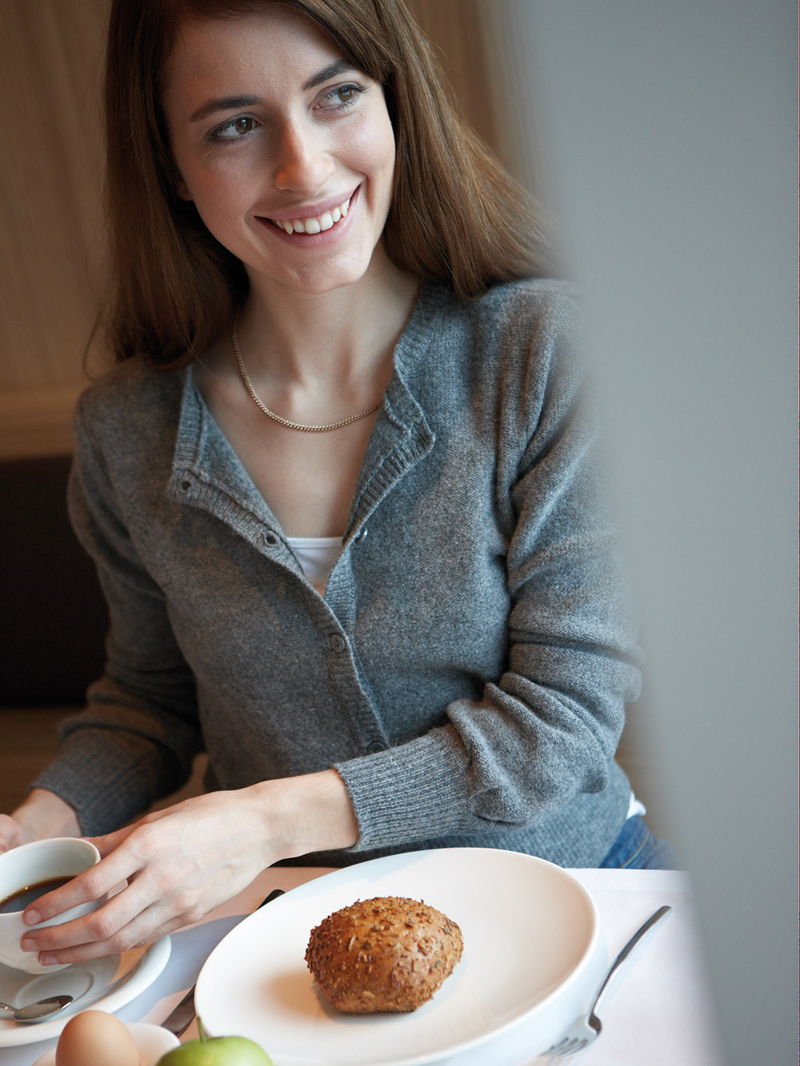 Frau am Frühstückstisch mit Kaffee und Brot