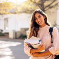 young_hispanic_female_carrying_books_on_college_campus young_hispanic_female_carrying_books_on_college_campus