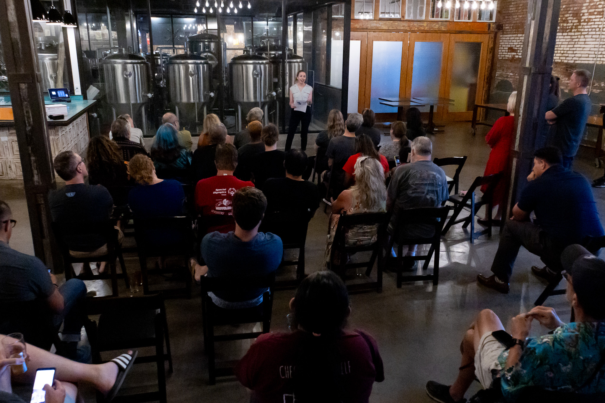 Crowd shot of people attending Bikes and Brews at Four Corners Brewery. In this photo, Kathryn Rush is speaking at the front of the room.