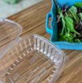 Salad greens being transfered from a Goodgaurd package to a decorative blue salad bowl