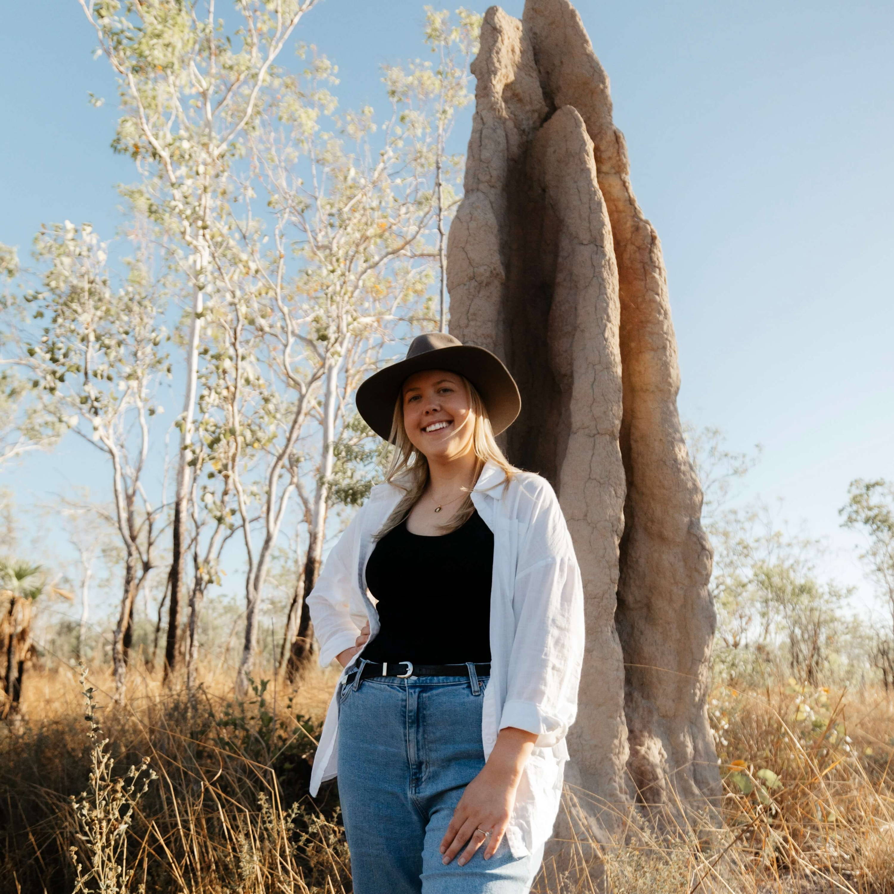 Caitlin Trindall stood in front of a huge termite mound 