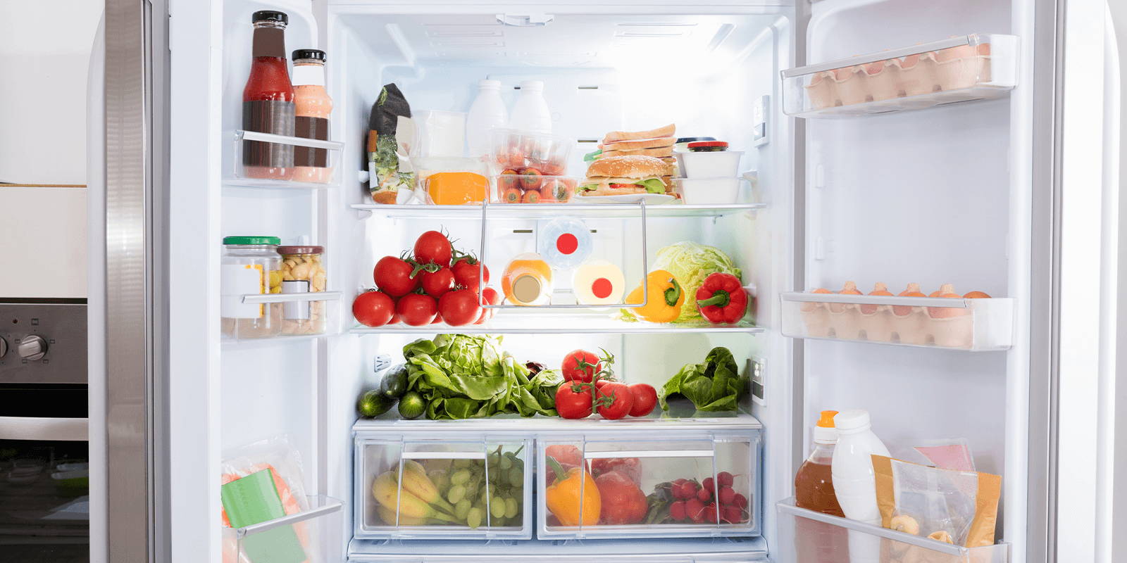 Fridge with open doors displaying fruits and vegetables.
