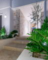 Layered pathway and garden lighting guiding entry with subtle illumination across stone and greenery