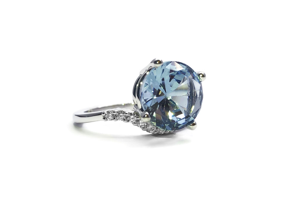 White gold ring on white background with sky blue topaz and diamonds