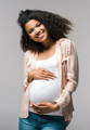 a pregnant woman holding her belly and smiling  - pregnant women can help maintain a healthy diet by including plenty of greens and vegetables