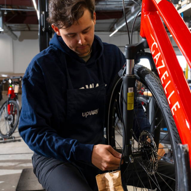 an Upway mechanic servicing a gazelle electric city bike