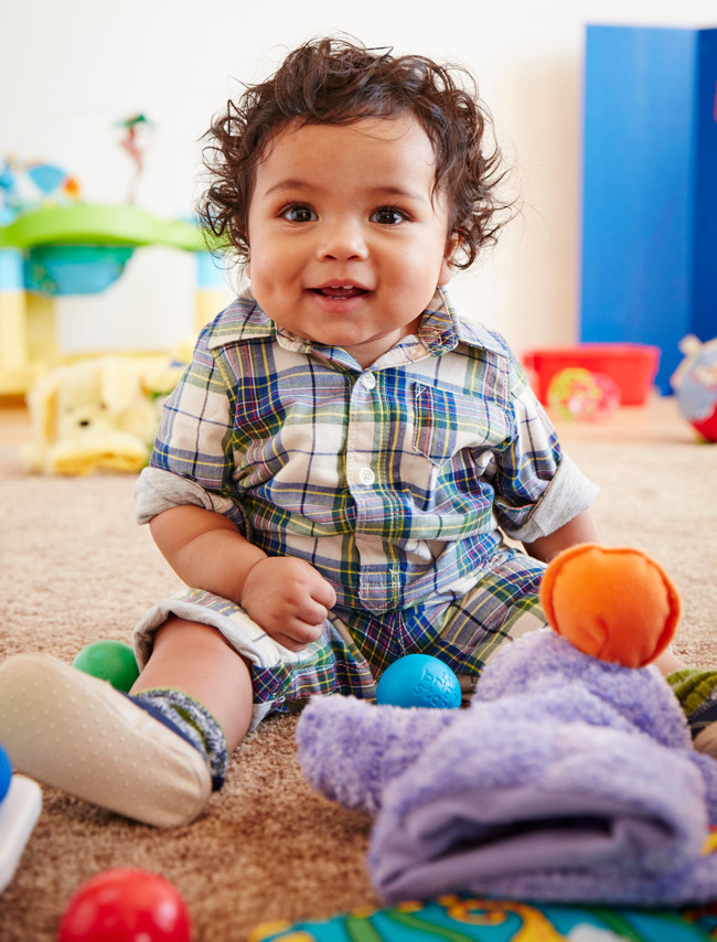 infant child smiling while holding a toy