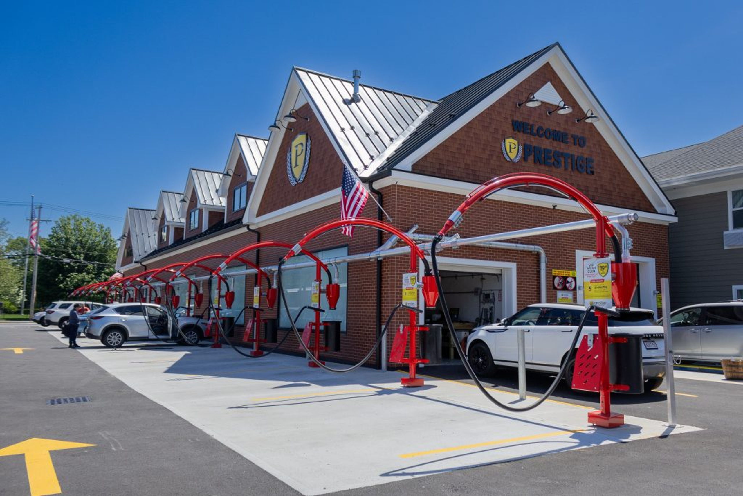 A Prestige Car Wash: the brick “Welcome to Prestige” building with the P shield, and a row of red free-vacuum arches along the lot