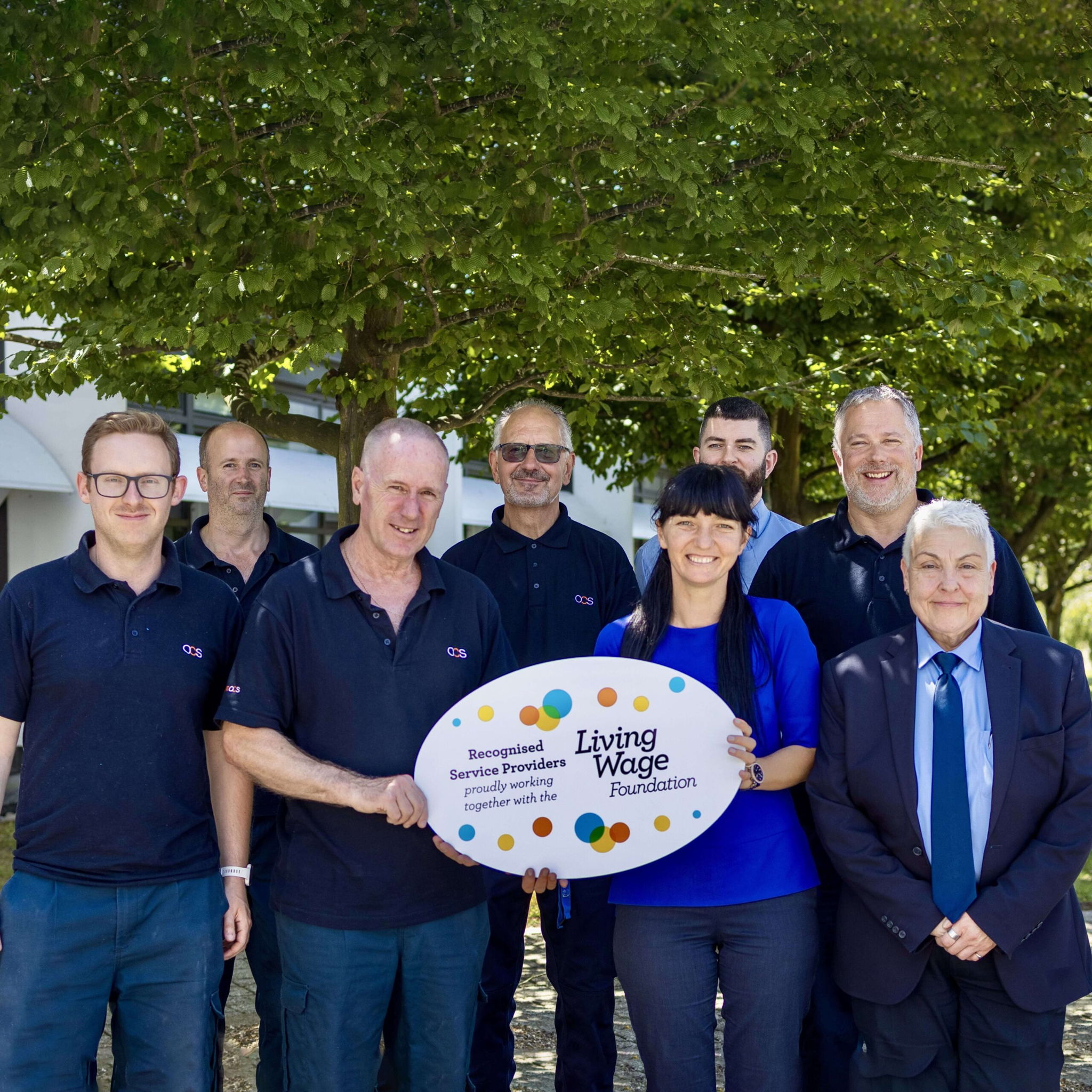 Group picture of OCS colleagues in uniform holding a sign