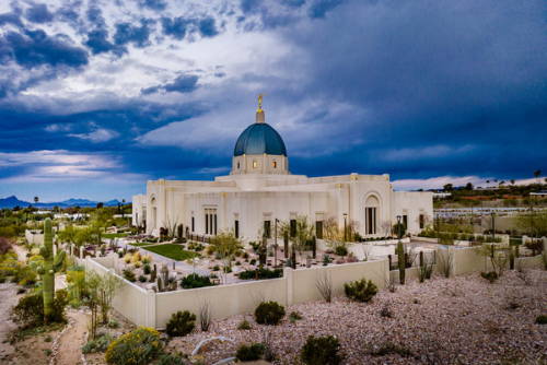 Tucson Temple picture featuring the desert landscape and blue storm clouds.