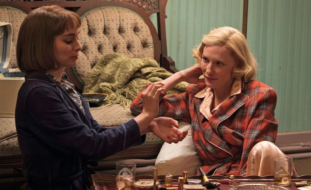 Carol looking lovingly at Thérese while she tries on perfume on her wrists.