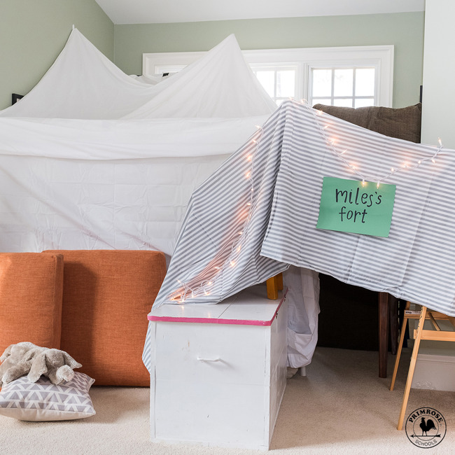 Indoor fort made with bed sheets and chairs labelled "Miles's fort"