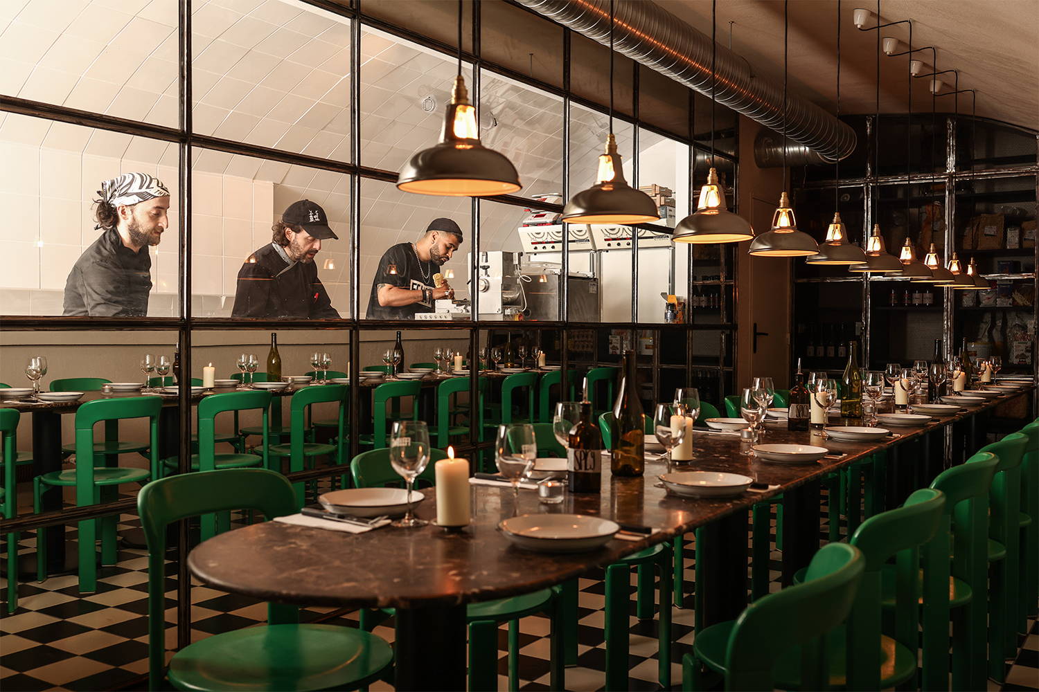 Original Coolicon Pendant lampshades inside a pasta restaurant, hanging above a long set table with green chairs.