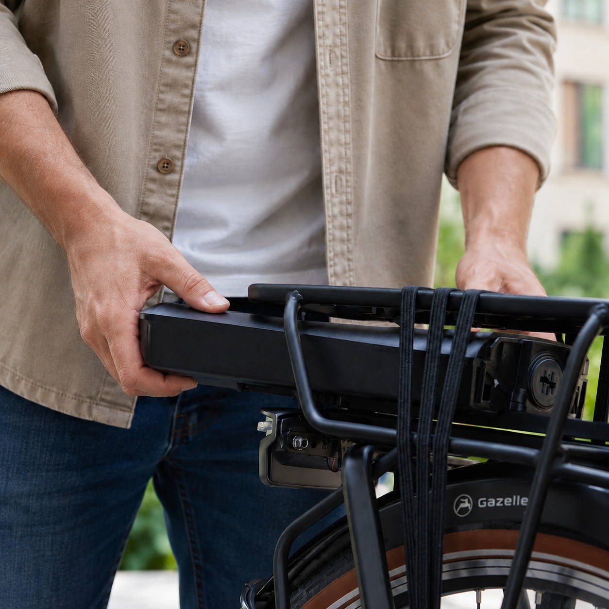 Man haalt de accu uit de bagagedrager van een elektrische fiets, als illustratie bij de actieradius van een Gazelle e-bike accu.