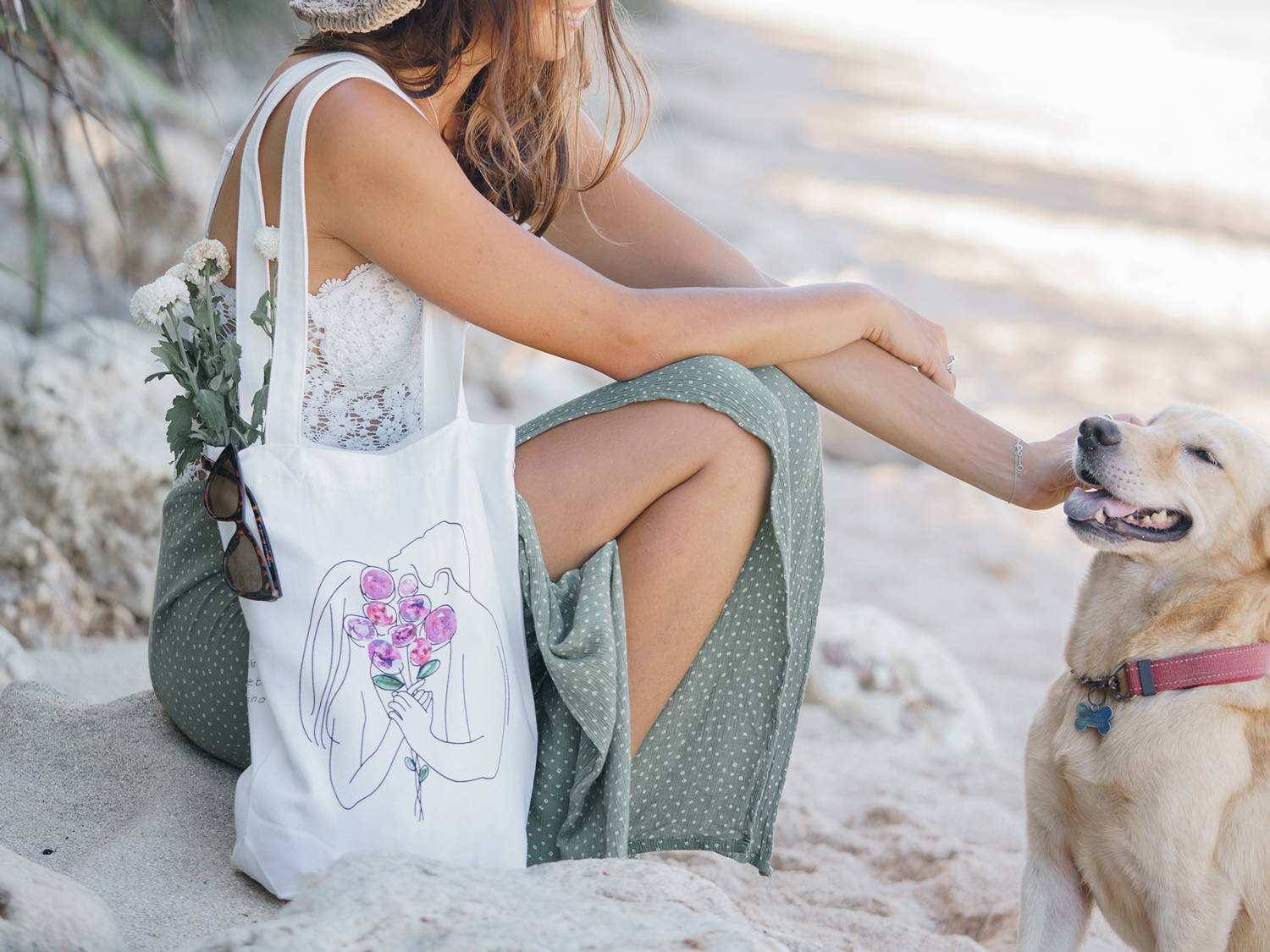 A woman and a dog at the beach with tote bag