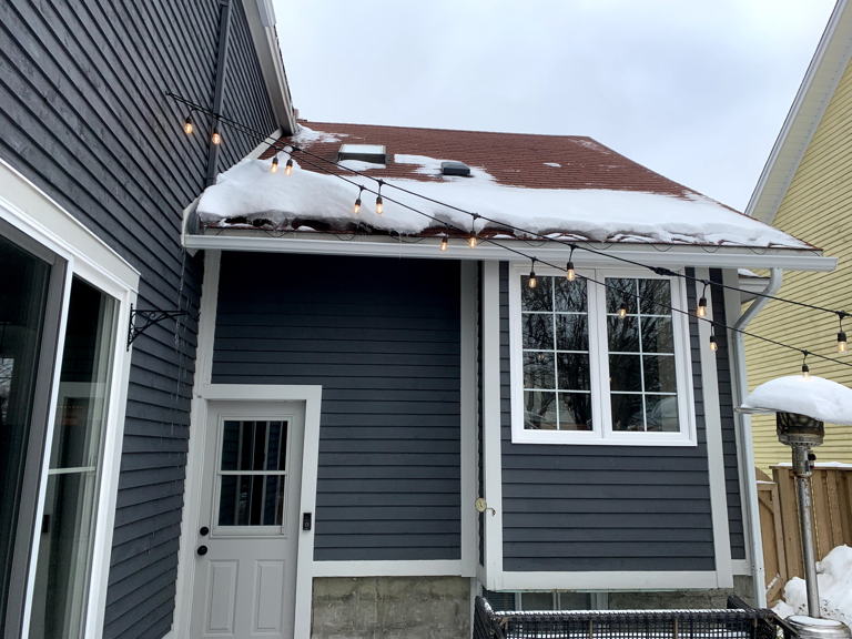 dark blue house with brown roof, white door and white trim