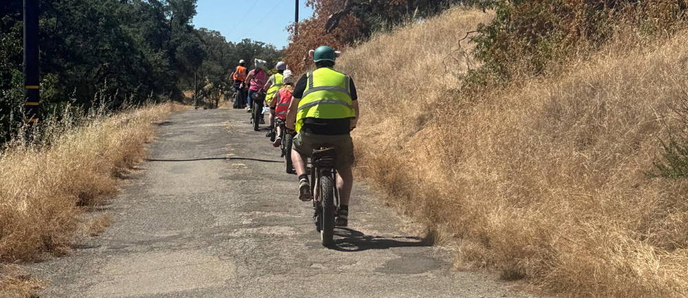 a large group of riders in a single file line on aventon aventure electric fat tire bikes in the sierra foothills on a tour with Yosemite E-Biking (yosemiteebiking.com)