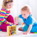 Brother and sister holding little bees while playing with Montessori Bee Box wooden toy. 