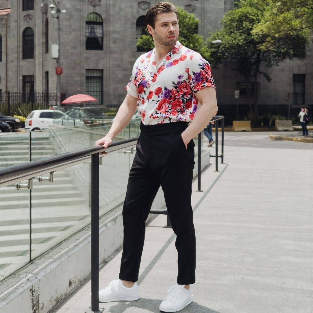 model standing in a plaza wearing white shoes black pants and a short sleeve white floral silk shirt from 1000 kingdoms