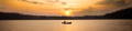 person paddling a canoe at sunset