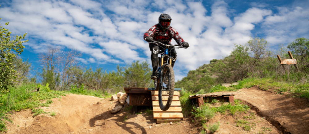 a man jumping a full suspension electric mountain bike off a ramp